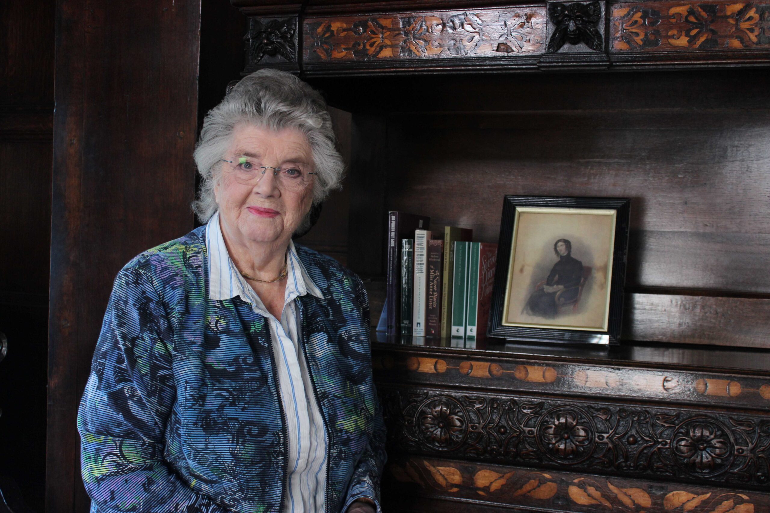 Photo of a woman with silver hair standing in front of a cabinet.